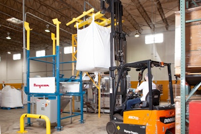 A forklift loads the lifting cradle with suspended bulk bag onto the discharger’s receiving cups.