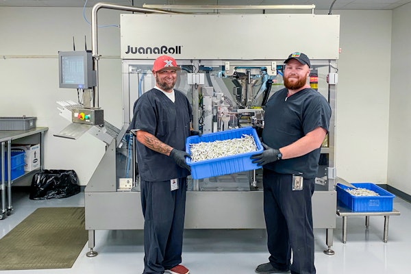 John Lamm, Juana Roll Technician Lead (left), and Elijah Streadwick, Assistant Manager (right), both of NGW, with product in front of the JuanaRoll eight-channel automatic pre-roll machine, available in models with from one to eight channels.