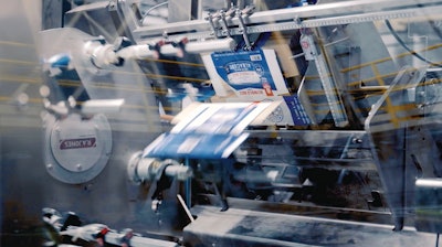 Printed paperboard cartons are opened out of magazines of 2D blanks by way of mechanical gripers, plus an “elegant” air-assist carton opening feature to ensure the cartons fully open.