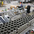 Brightstock cans are depalletized overhead on a high-trim Ska Can-i-Bus, then single-filed and lowered through a twist rinser on the way to the filler and seamer.