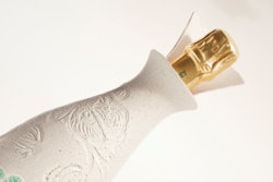 The Belle Epoque Cocoon exhibits an organic shape that gently enfolds the bottle. At the top, the golden cap of the bottle is revealed, surrounded by a petal-like, molded-pulp collar.