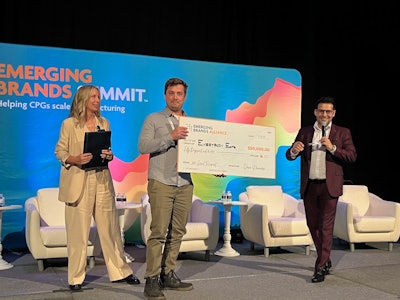 James Vierck, Operations Manager for Every Body Eat, accepts the grant award at the Emerging Brands Summit in Las Vegas as EBA Director Kim Overstreet and MC Ivan Ruiz look on.