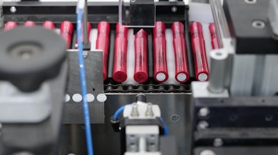 Circular bottom labels are applied after a 90-degree turn orients the tubes from end-to-end, to side-by-side. On-tube and on-label coding and marking is done in the stage.