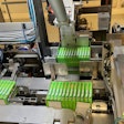 Shown here in the tray packer are one 12-count group of cartons in the flap compression station, another in the tray load station, and a third that is about to be pushed into the tray load station.