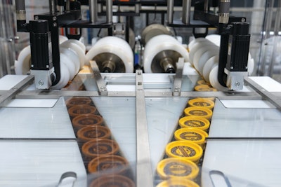 Single-filed cups of vanilla and single-filed cups of chocolate are shown here entering the Morrison turning and grouping screws.