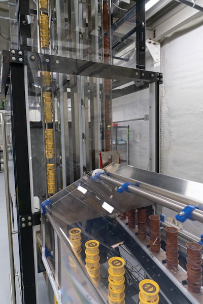 Cups ride in groups of six down parallel elevators and are then pushed at a right angle onto two parallel flighted conveyors.