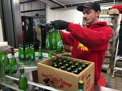 Filled and crowned bottles rotate on a Multi-Conveyor accumulation table before being inspected and hand-packed into cases.