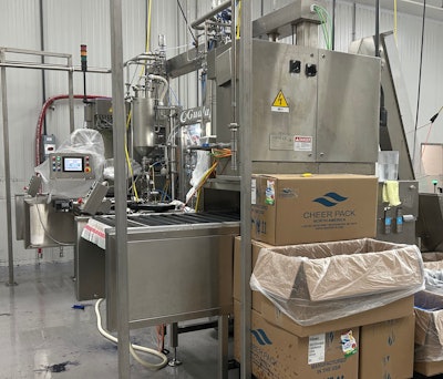 Before HPP and case packing is phase one, where spouted pouches mounted on rails are fed into a two-head rotary filler.