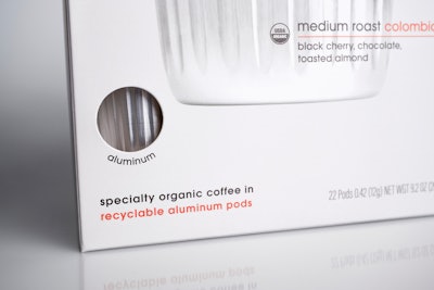 A die-cut window in the coffee carton provides a view of one of the aluminum pods inside the carton.