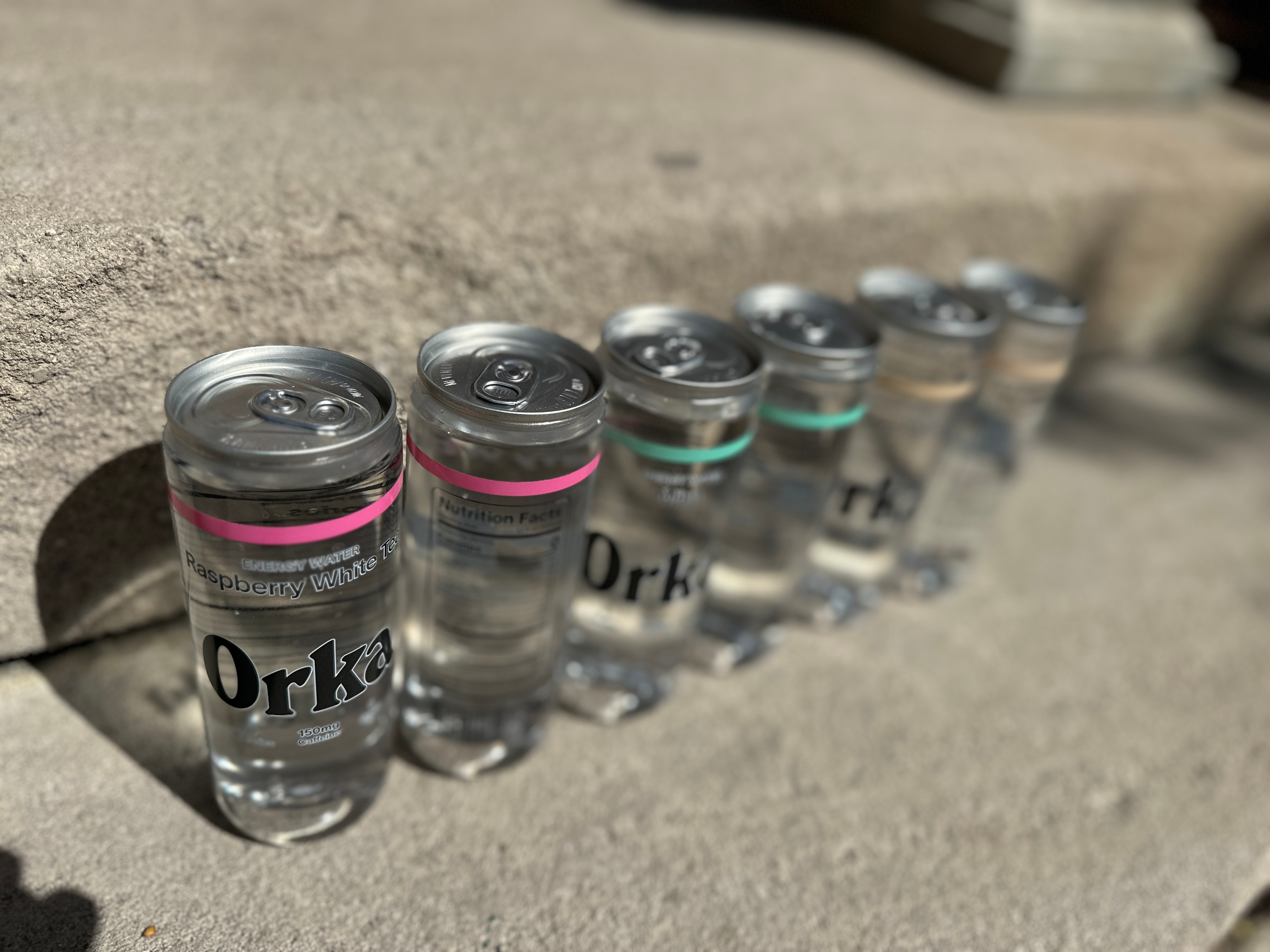 Orka energy drinks are filled in a PET bottle with aluminum closures seamed on, and what appears to be a lightly printed, otherwise transparent pressure-sensitive PE label.