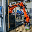 Orange KUKA robotic arm performing automated packaging on wooden pallet