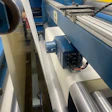 Industrial machinery with blue metal components and large cylindrical rollers