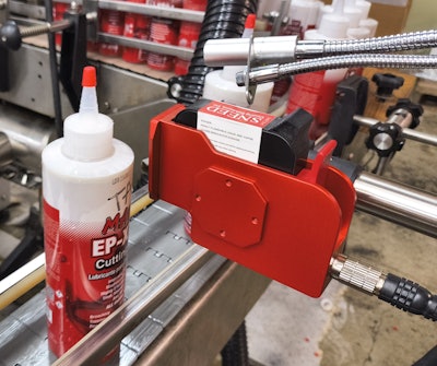 Lot and date code information is printed on the labeled container by this ink-jet printer.