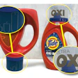 Tide’s polypropylene caps undergo LaserSharp marking on two sides. On the left, we see an inverted bottle where Tide’s blue detergent is completely filling the dosing cap. Fill-level guidelines are visible both when detergent is in the cap as pictured, and when the cap is empty. On the upper right, we see the OXI logo on the other side of the cap. This branding/logo was also marked on the cap in the LaserSharp process.