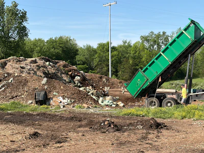 Waste haulers unload collected food scraps and compostable materials at The Compost Company, where the material is then mixed with wood waste and prepared for grinding before entering the active composting process.