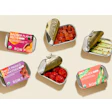 Row 7’s tinned vegetables are packed in small-format tins with paperboard sleeves that leave the container visible, reinforcing the brand’s produce-aisle positioning and connection to fresh, flavor-bred vegetables.