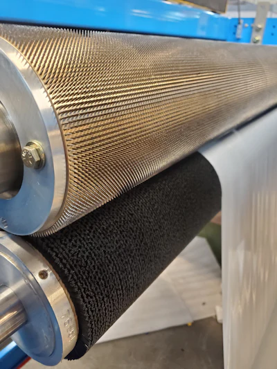 A typical perforating nip with a pinned roller against a brush anvil roller, with the material sandwiched between the two.