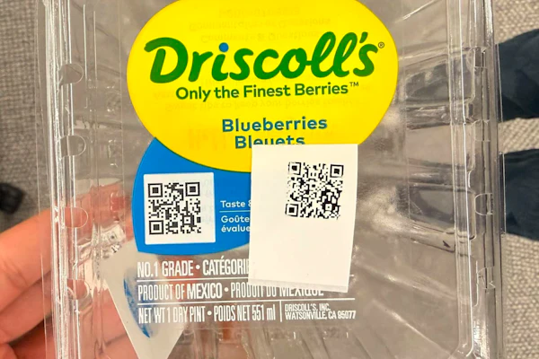 A Driscoll's blueberry clamshell carrying two QR codes — one pre-printed on the brand label, one applied at the farm. Together they're central to a serialization program that has given more than a billion packages a unique, traceable identity.