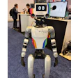 Sumay, a humanoid powered by OpenMind's software, draws a crowd at Automate 2026's Humanoid Robot Pavilion. The engineering impresses, but bipedal humanoids remain a few cycles away from the packaging floor.