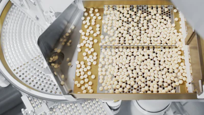 Overhead view of white pharmaceutical capsules or pills arranged on cardboard trays during quality control inspection with metal tool