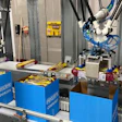 Industrial 3D printer and manufacturing equipment in a workshop with blue storage containers and machinery