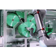 Robotic arm assembling green cooling fans in an industrial manufacturing system with metallic framework.