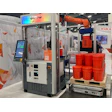KUKA industrial robotics exhibition booth with automated arm system and red industrial containers on display