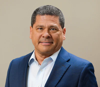 Professional headshot of a man in blue blazer and light blue shirt against neutral background