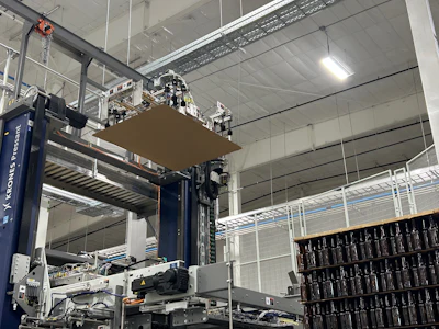 In addition to sweeping layers of bottles from full pallets, the depalletizer removes and stacks slip sheets.