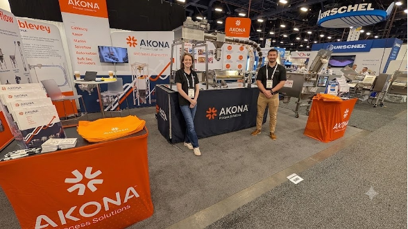 AKONA trade show booth with orange branding, staff members, and company signage at exhibition event