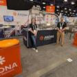 AKONA trade show booth with orange branding, staff members, and company signage at exhibition event