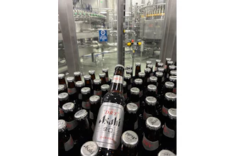 Both 12-oz (shown) and 21-oz bottles are filled on the line, and body labels in both cases promote the “Brewed in the USA” message.