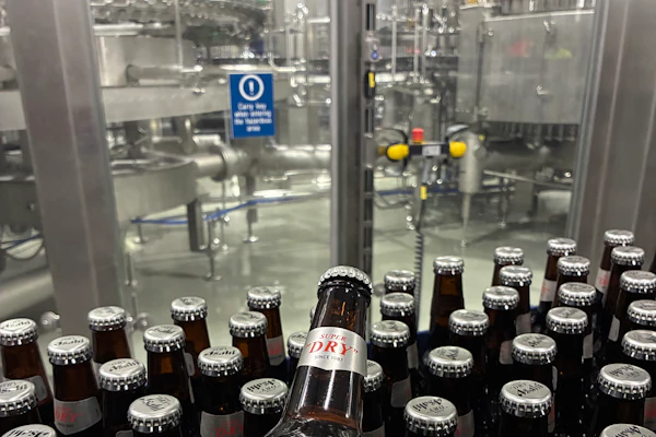 Both 12-oz (shown) and 21-oz bottles are filled on the line, and body labels in both cases promote the “Brewed in the USA” message.