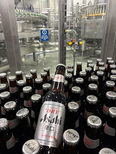 Both 12-oz (shown) and 21-oz bottles are filled on the line, and body labels in both cases promote the “Brewed in the USA” message.