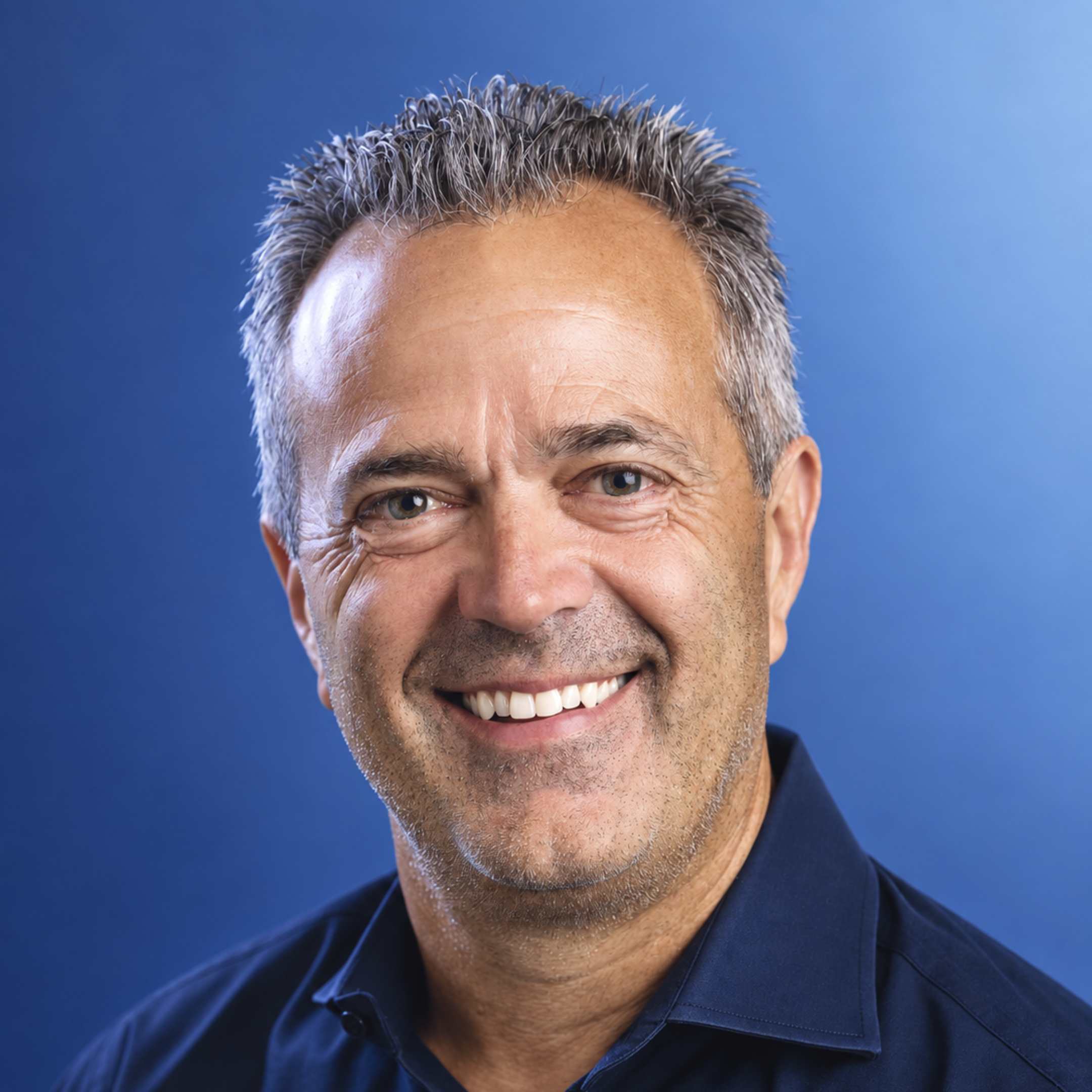 Professional headshot of smiling middle-aged man in dark blue shirt against blue background