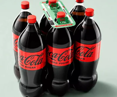 The alternative format holds individual PET bottles together using strategically positioned adhesive dots, with a rigid cardboard carrying handle fitted to the assembled pack.