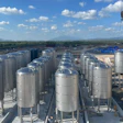 Industrial storage facility with rows of large cylindrical metal tanks and yellow mobile crane on construction site