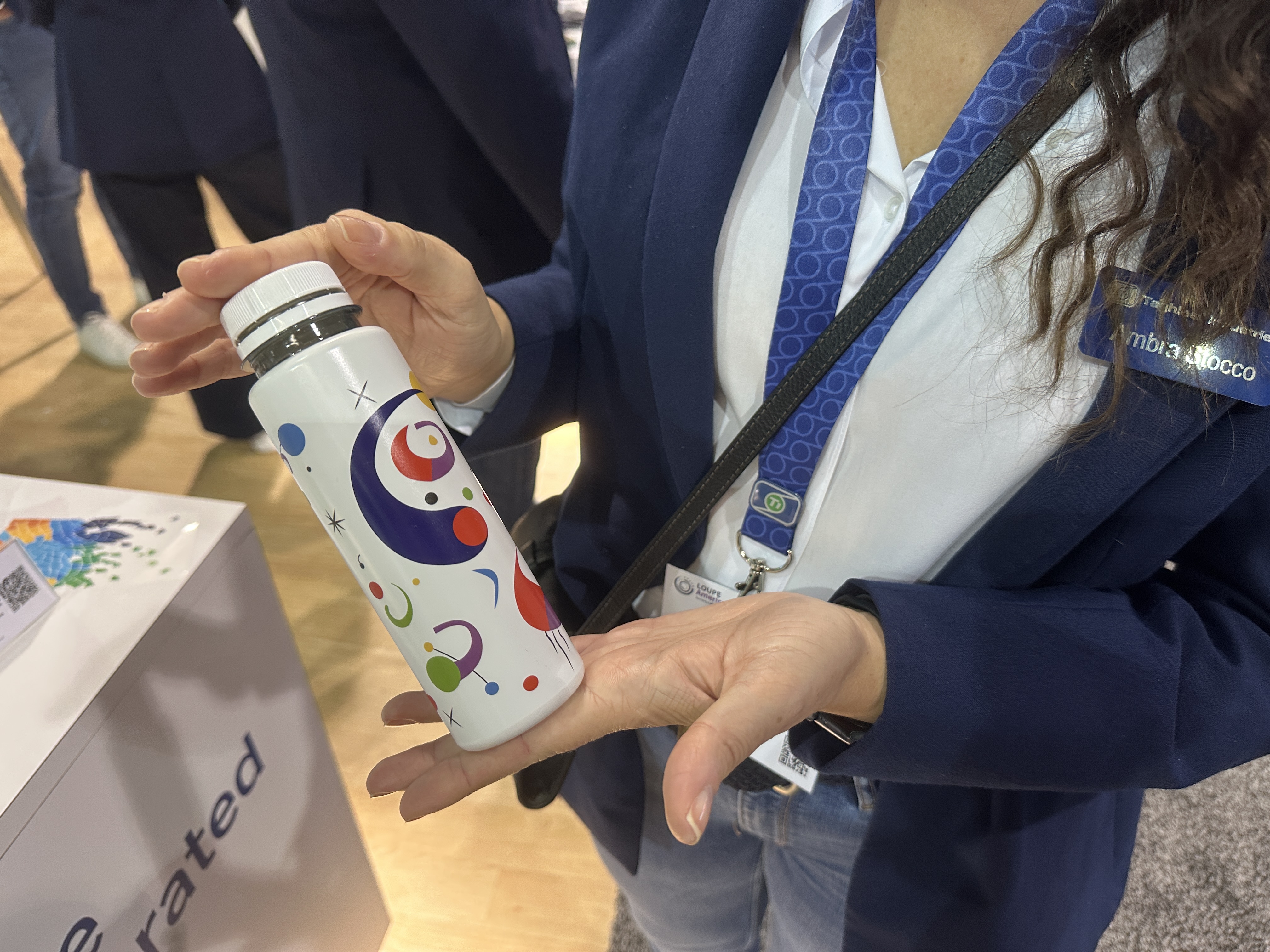 Ambra Stocco of Taghleef Industries holds a sample bottle with the company's shrink sleeve film at Loupe Americas.