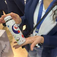 Ambra Stocco of Taghleef Industries holds a sample bottle with the company's shrink sleeve film at Loupe Americas.