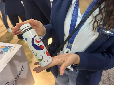 Ambra Stocco of Taghleef Industries holds a sample bottle with the company's shrink sleeve film at Loupe Americas.