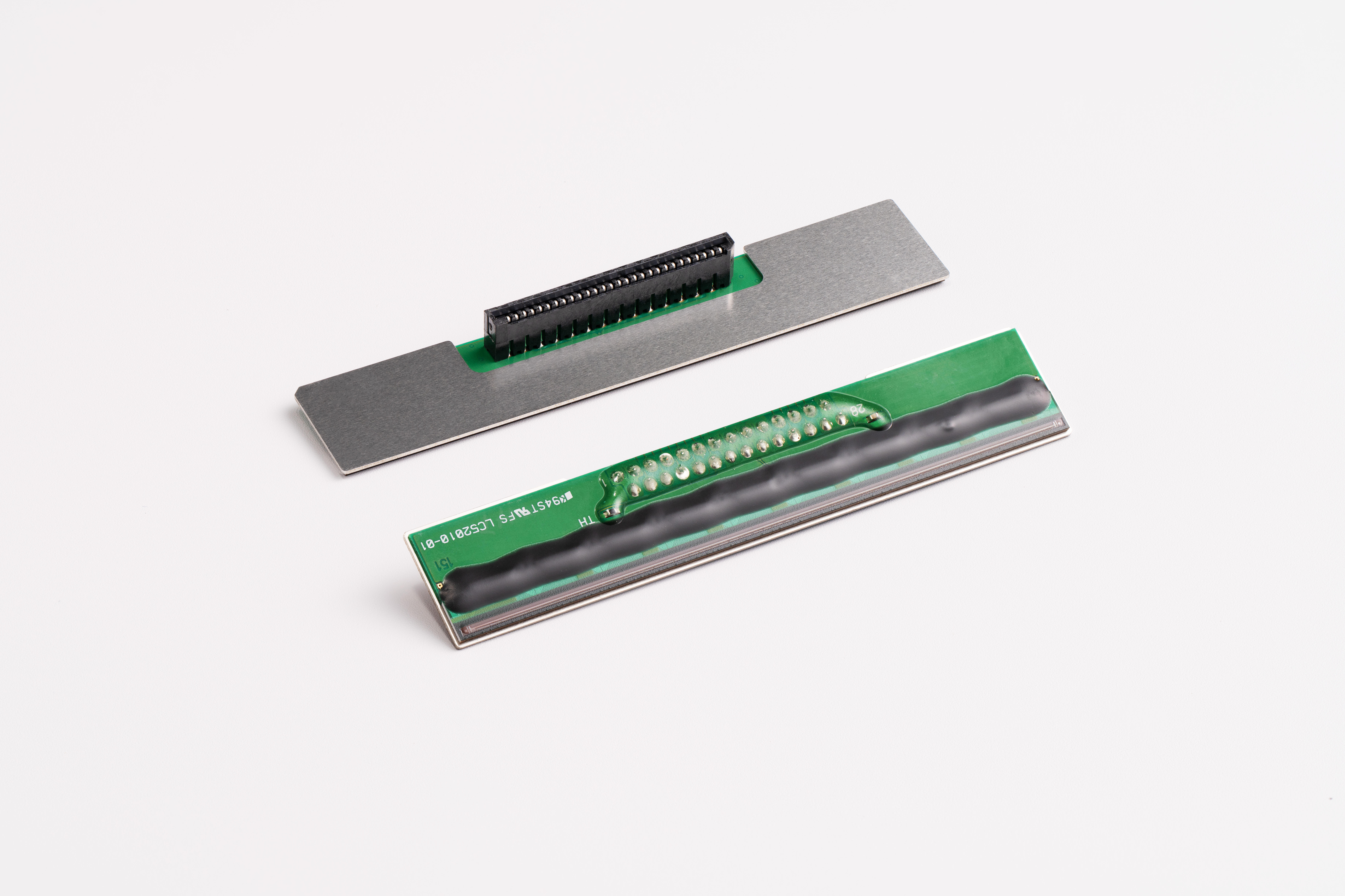 Thermal printer head components showing metal plate and green circuit board assembly