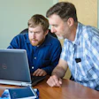 Two professionals collaborating at a laptop during a meeting or training session