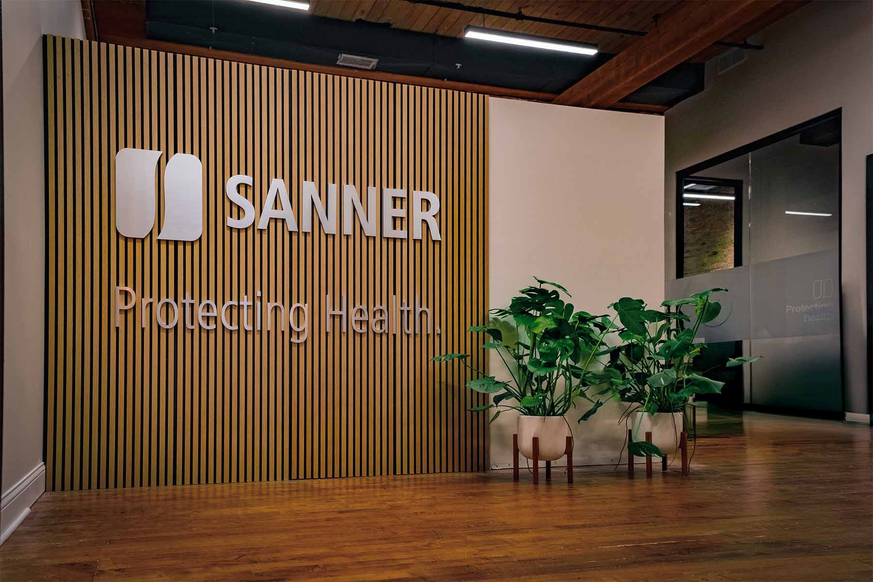 SANNER corporate office lobby with modern wooden slat wall signage and potted plants