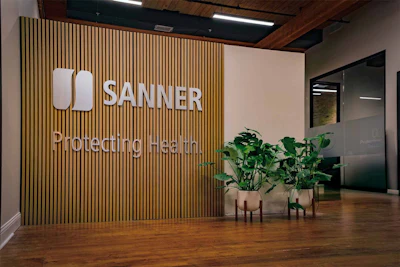 SANNER corporate office lobby with modern wooden slat wall signage and potted plants