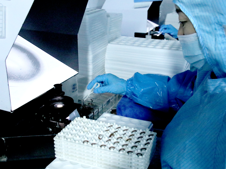 Laboratory technician in protective gear handling samples in a biosafety cabinet during scientific research