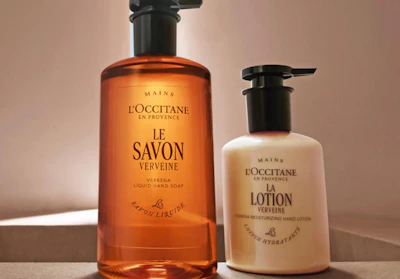 L'Occitane Verveine hand soap and lotion bottles with pump dispensers on neutral background