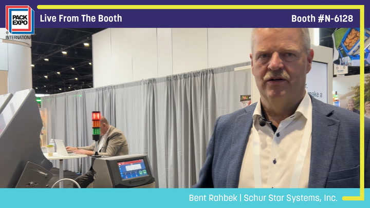 Professional man in blue blazer at Pack Expo booth N-6128 featuring Schur Star Systems equipment and signage