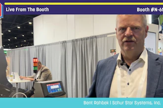 Professional man in blue blazer at Pack Expo booth N-6128 featuring Schur Star Systems equipment and signage
