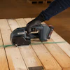 Worker using cordless power tool on wooden deck planks with green chalk line