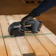 Worker using cordless power tool on wooden deck planks with green chalk line